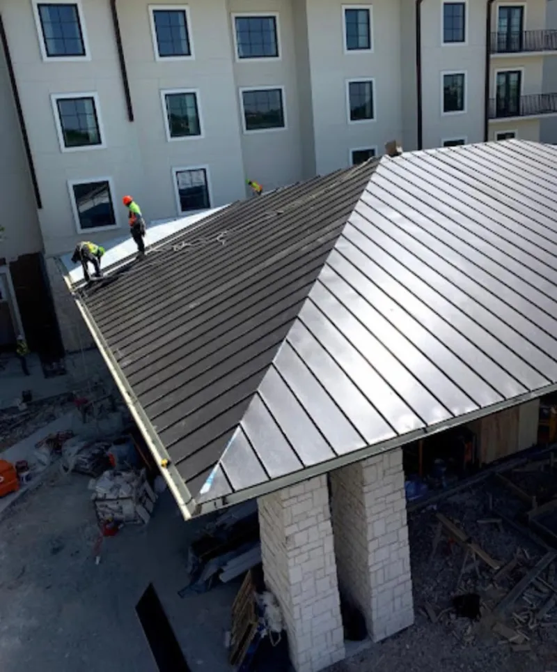 Crew installing standing seam metal roof panels on a commercial project in Grandville